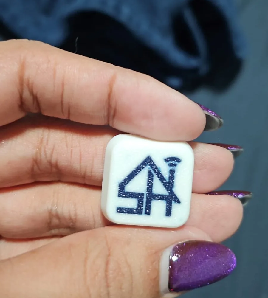 Tecla impresa en 3D con el logo de una empresa, sostenida en la mano